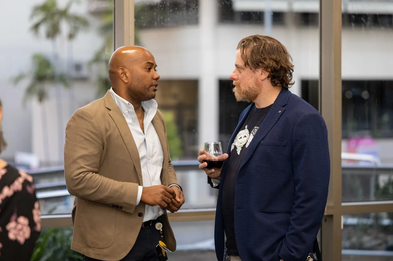 Two guests talk by a window at the 18 July 2024 launch of PTR's VR Training Library in Townsville.