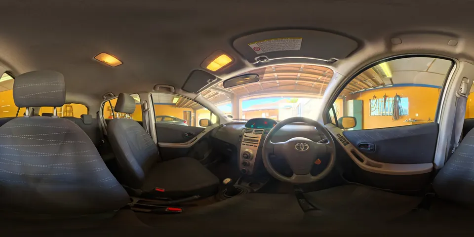 A car interior in a garage. The whole 360 sphere of the scene unwrapped into one wide strip, as the viewer stores it.