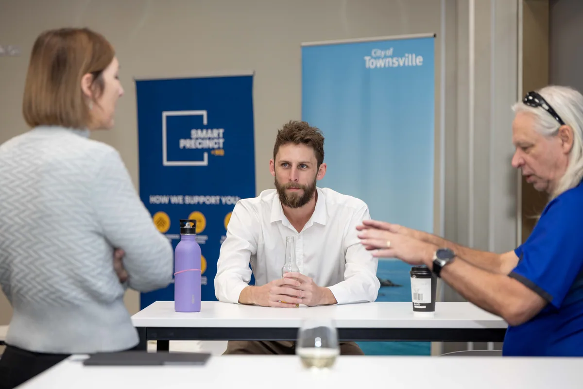 A conversation at the table by the banner. PTR VR Library public launch at Smart Precinct NQ, Townsville, 18 July 2024.