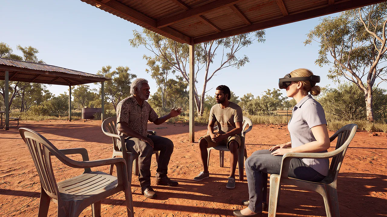 An Elder in his mid-sixties sits with a young man from his community; a mediator wearing the headset sits outside their circle, rehearsing a mediation conversation.